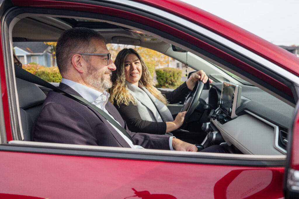 Two people chat while in a carpool in a red car